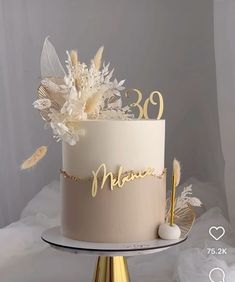 a white and gold birthday cake with feathers on the top that says'30th '