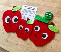 two red apples with eyes and a worm on them