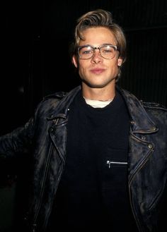 a man wearing glasses and a black shirt is posing for the camera with his arms outstretched