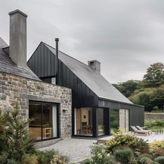 a house with black shingles and stone walls