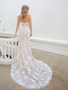 a woman in a wedding dress looking down at the stairs