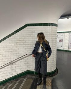 a woman standing at the top of an escalator with her hand on her hip