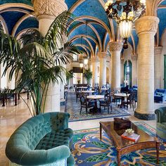 an ornately decorated lobby with couches and tables in the center, surrounded by columns