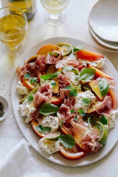 a white plate topped with lots of food on top of a table next to glasses