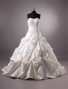 a white wedding dress on display in front of a gray background