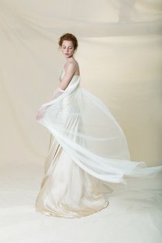 a woman in a white dress is posing for the camera with her long flowing veil