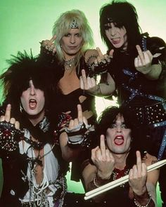 the band kiss posing for a photo with their hands in the air and holding up two fingers