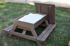 a child's wooden table and chair sitting in the grass