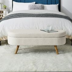 a white bed with a blue headboard and foot stool