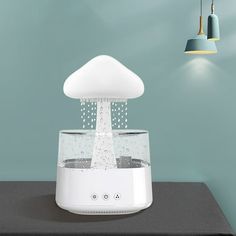 an image of a water fountain that is on top of a table in front of a lamp