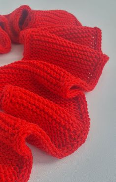 a red knitted scarf laying on top of a white table