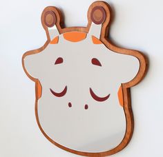 a white and orange animal shaped mirror hanging on the side of a wall next to a wooden frame