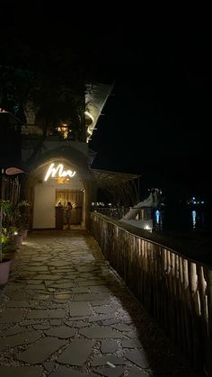 the walkway is lit up at night with lights on and plants in pots along it