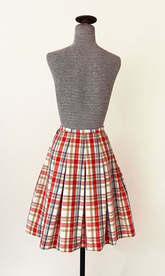 "1960s Miss Pat pleated skirt. Light red, blue, gold and white plaid pattern. High waisted with dropped pleats and a wide A line cut. Side zipper and button closure. In great vintage condition with a couple tiny specks - please see photos. All measurements are taken with the garment laying flat and doubled for the bust, waist, and hips. Waist: 22\" Hips: open Length: 22\" Label: Miss Pat Material: Not listed; looks / feels like cotton or cotton blend Size on Tag: N/A Approx. Fit: XXS Some garmen Classic Pleated Plaid Skirt, Retro Fitted Cotton Pleated Skirt, Retro Pleated Mini Skirt, Vintage Fitted Accordion Pleated Skirt, Plaid Flared Pleated Lined Skirt, Plaid Flared Pleated Skirt With Lining, Vintage Full Skirt With Accordion Pleats, Retro Accordion Pleated Skirt For Fall, Retro A-line Pleated Skirt