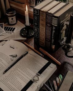 an open book sitting on top of a table next to a candle and some books