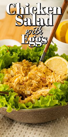 chicken salad with eggs and lettuce in a bowl on a table next to lemons