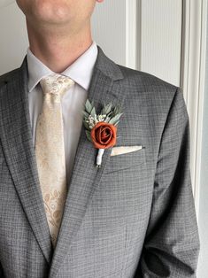 a man wearing a suit and tie with a boutonniere on his lapel