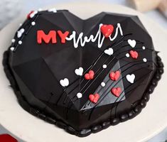 a black heart shaped cake with red and white hearts on it that says my love