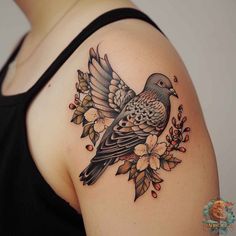 a woman's shoulder with a bird and flowers tattoo on her left side arm