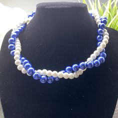 Enhance your ensemble with a touch of regal elegance through this exquisite Blue White Pearl Twisted Necklace. Crafted with meticulous attention to detail, this stunning accessory is designed to elevate any occasion. The captivating twisted pattern, adorned with a harmonious blend of blue and white pearls, exudes a timeless charm that will effortlessly enhance your overall look. Rest assured, the lobster claw clasp ensures a secure closure, while the adjustable length allows for a personalized f Elegant Royal Blue Round Bead Necklaces, Elegant Royal Blue Round Beads Necklace, Elegant Royal Blue Round Beaded Necklace, Elegant Blue Necklace With Round Beads, Elegant Blue Pearl Necklace, Blue Pearl Jewelry For Party, Party Pearl Jewelry In Blue, Elegant Blue Pearl Necklace For Formal Occasions, Blue Pearl Necklace For Gift