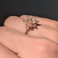 a woman's hand with a ring on it that has a flower shaped diamond in the middle