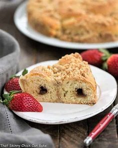 a piece of crumbly bread on a plate with strawberries next to it