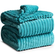 three towels stacked on top of each other in turquoise colors, one folded and the other rolled up