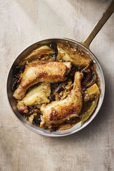 a pan filled with chicken and vegetables on top of a wooden table