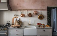 a kitchen with pots and pans hanging on the wall next to an open stove