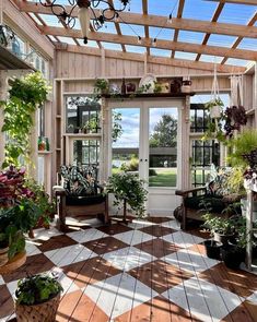 a room filled with lots of potted plants on top of wooden flooring next to windows