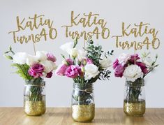 three mason jars filled with flowers on top of a table