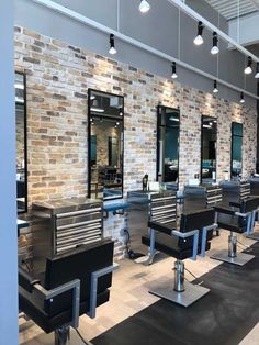 the interior of a hair salon with black and white chairs, brick walls and mirrors