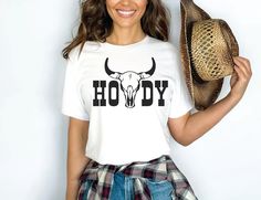 a woman wearing a white shirt with the word hodgy on it and a straw hat