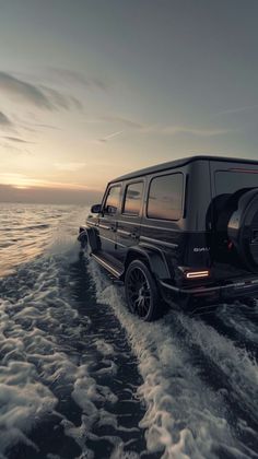 the mercedes benz g - class is driving on the water at sunset or dawn with clouds in the sky