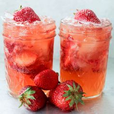 two glasses filled with ice and strawberries next to each other