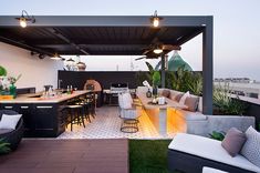 an outdoor kitchen and dining area on the roof of a building with potted plants