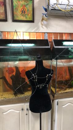 a black mannequin in front of an aquarium with gold chains on it's neck