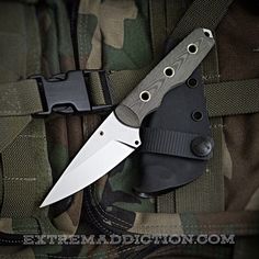 a knife is laying on the back of a camouflage jacket with its blade stuck in it's pocket