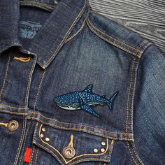 a denim jacket with a shark embroidered on it