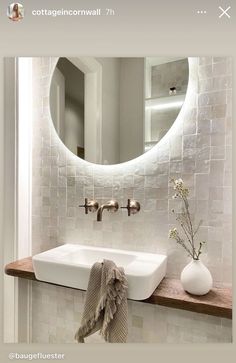 a white sink sitting under a round mirror