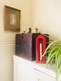 two pieces of wood sitting on top of a white shelf next to a plant and candle holder