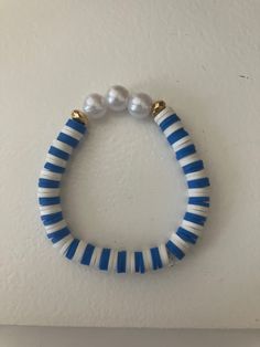 a blue and white beaded bracelet with two pearls on the end, hanging from a wall