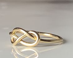 were highly symbolic in vintage jewelry, symbolizing infinite love. This would make a wonderfully unique wedding or engagement ring due to the romantic symbolism. The love knot/infinity knot represented the union of two souls arranged in the form of an infinity love knot. :) Ring weighs 1.3 grams. Band is stamped for 14k gold and is nice and sturdy despite it's dainty appearance. The ring is very comfortable to wear due to the low profile. The setting face measures 12.5 mm E to W and 8 N to S. C Wedding Infinity Jewelry With Ring Detail, Symbolic Infinity Jewelry For Anniversary, Infinity Ring Detail Wedding Jewelry, Cabin Core Aesthetic, Celtic Knot Promise Ring, Knotted Gold Ring, Gold Love Knot Ring, Heart Knot Ring, Cabin Core