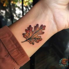 a leaf tattoo on the wrist is shown in black and red ink, with an orange color