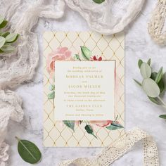 the wedding stationery is laid out on a marble surface with flowers and greenery