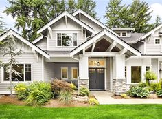 a house that is in the grass with trees and bushes around it's front door