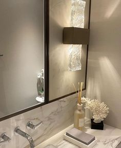 a bathroom sink sitting under a mirror next to a vase with flowers on top of it