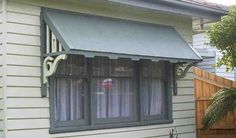 a white house with a green awning on the front and side of it's windows