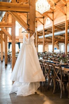 a wedding dress hanging from a chandelier in a room filled with tables and chairs