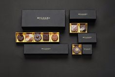 four different types of chocolates in black and gold boxes on a dark surface with the words buvelcari